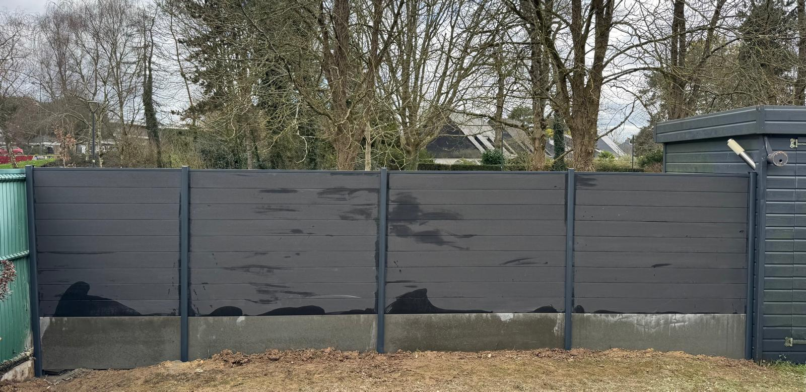 Clôture occultante grise installée dans un jardin